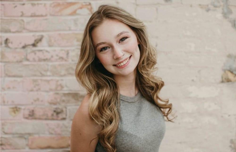Image 1 of 2 female student standing in front of a brick wall